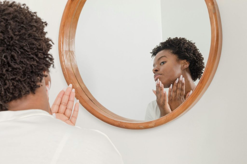 Strengthen & Glow: The Power of Skin Barrier Repair Treatments at Crystalline Clinic Photo - A woman looking in the mirror thinking about Skin Barrier Repair Treatments