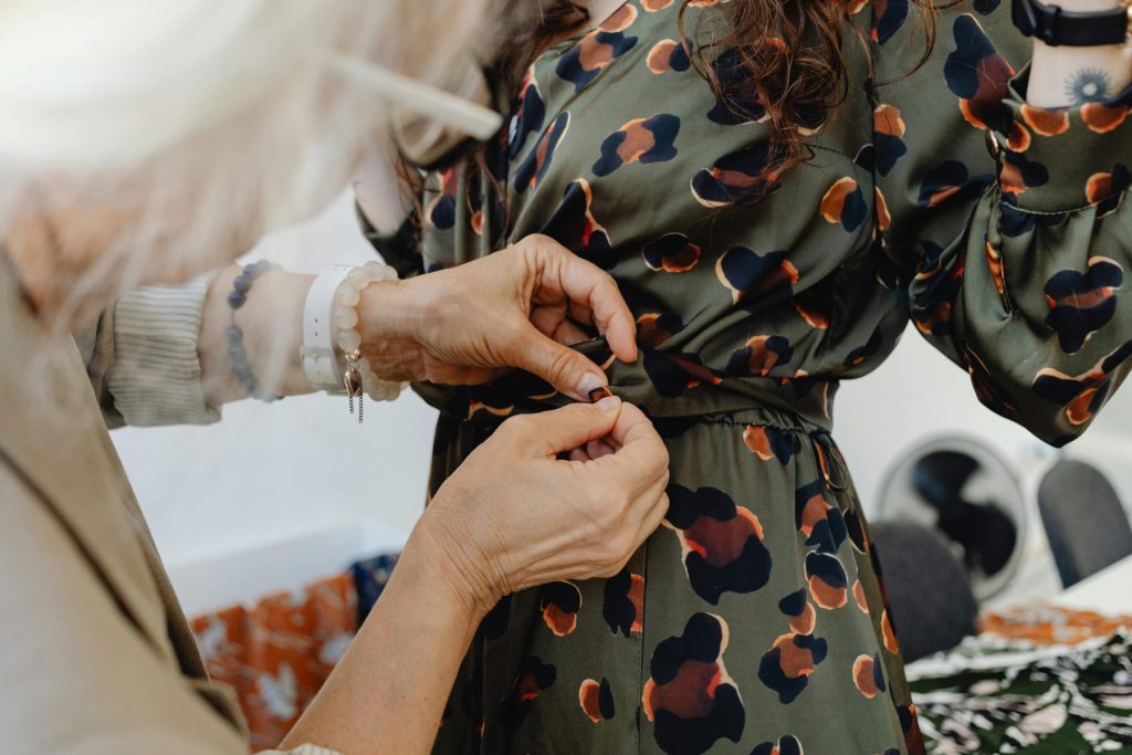 Photo - An older lady tying up another womans dress